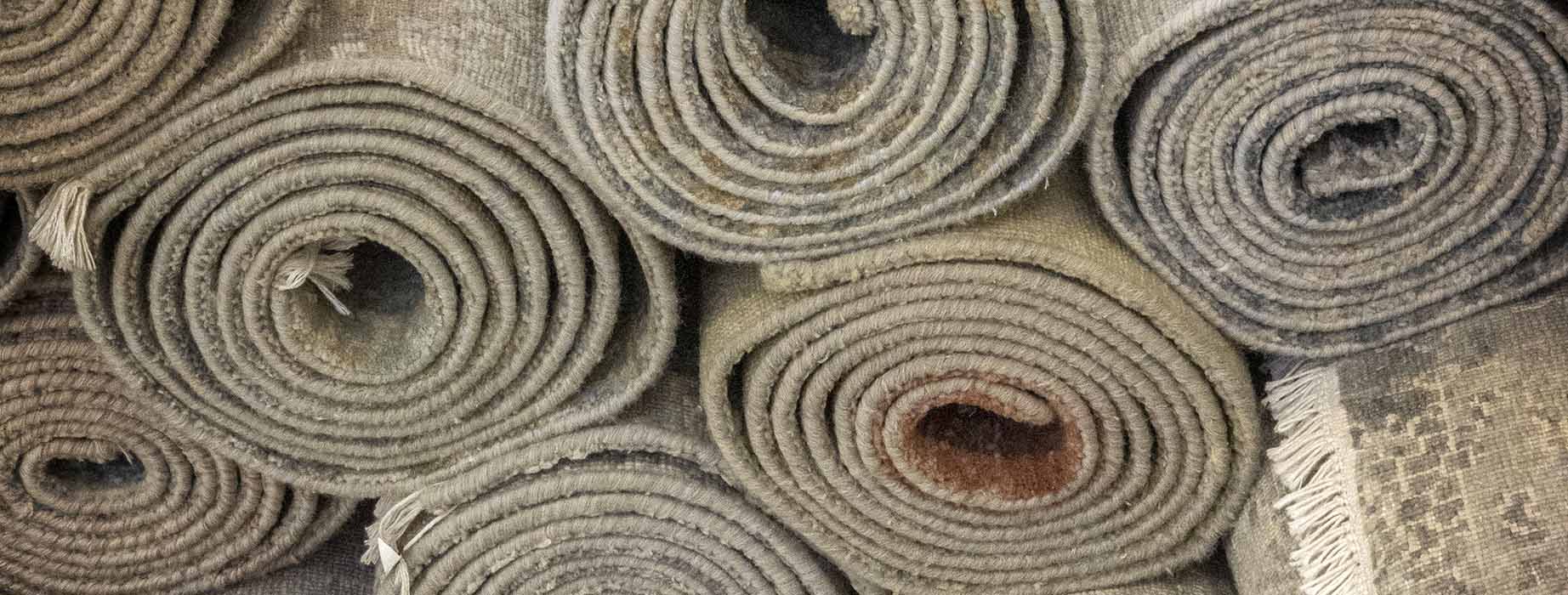 A wide selection of fine handmade and hand knotted area rugs rolled up in a pile.